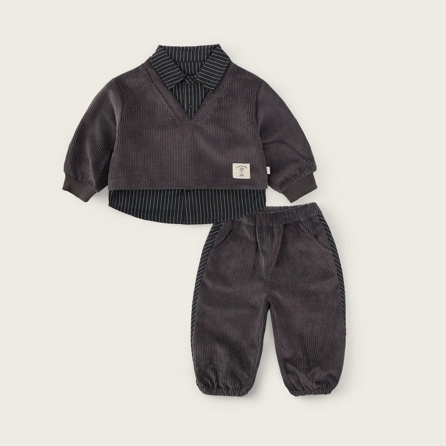 A baby clothing set from Jacinda Bebe, featuring a dark gray corduroy long-sleeve top with a striped shirt collar and matching corduroy pants, displayed on a light beige background with brand text.