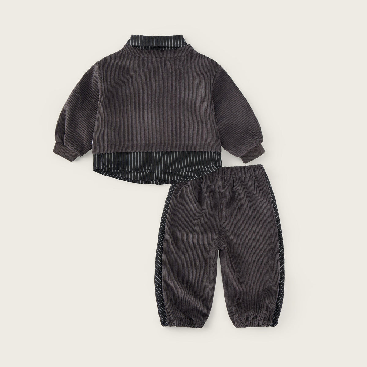 A two-piece baby outfit set in dark gray corduroy, featuring a long-sleeve mock-neck top with ribbed trim and matching jogger pants with corduroy side panels, displayed on a light beige background with 'jacinda bebe' and 'lovely kids' text.