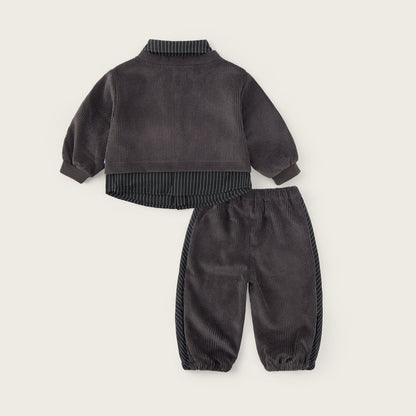 A two-piece baby outfit set in dark gray corduroy, featuring a long-sleeve mock-neck top with ribbed trim and matching jogger pants with corduroy side panels, displayed on a light beige background with 'jacinda bebe' and 'lovely kids' text.