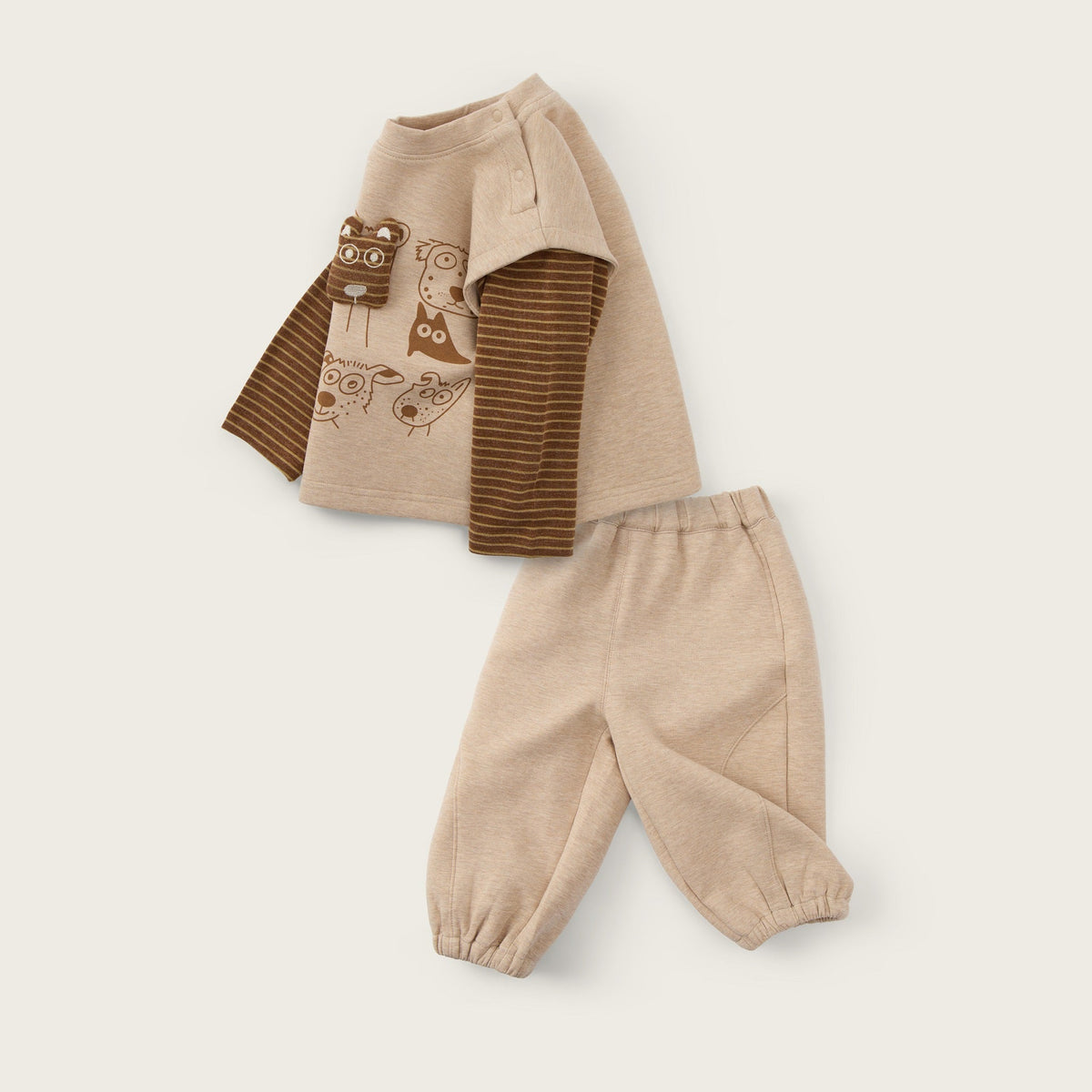 A baby clothing set featuring a beige long-sleeve top with brown striped sleeves and a brown animal graphic, paired with matching beige pants, displayed on a light beige background with 'jacinda bebe' and 'lovely kids' text.
