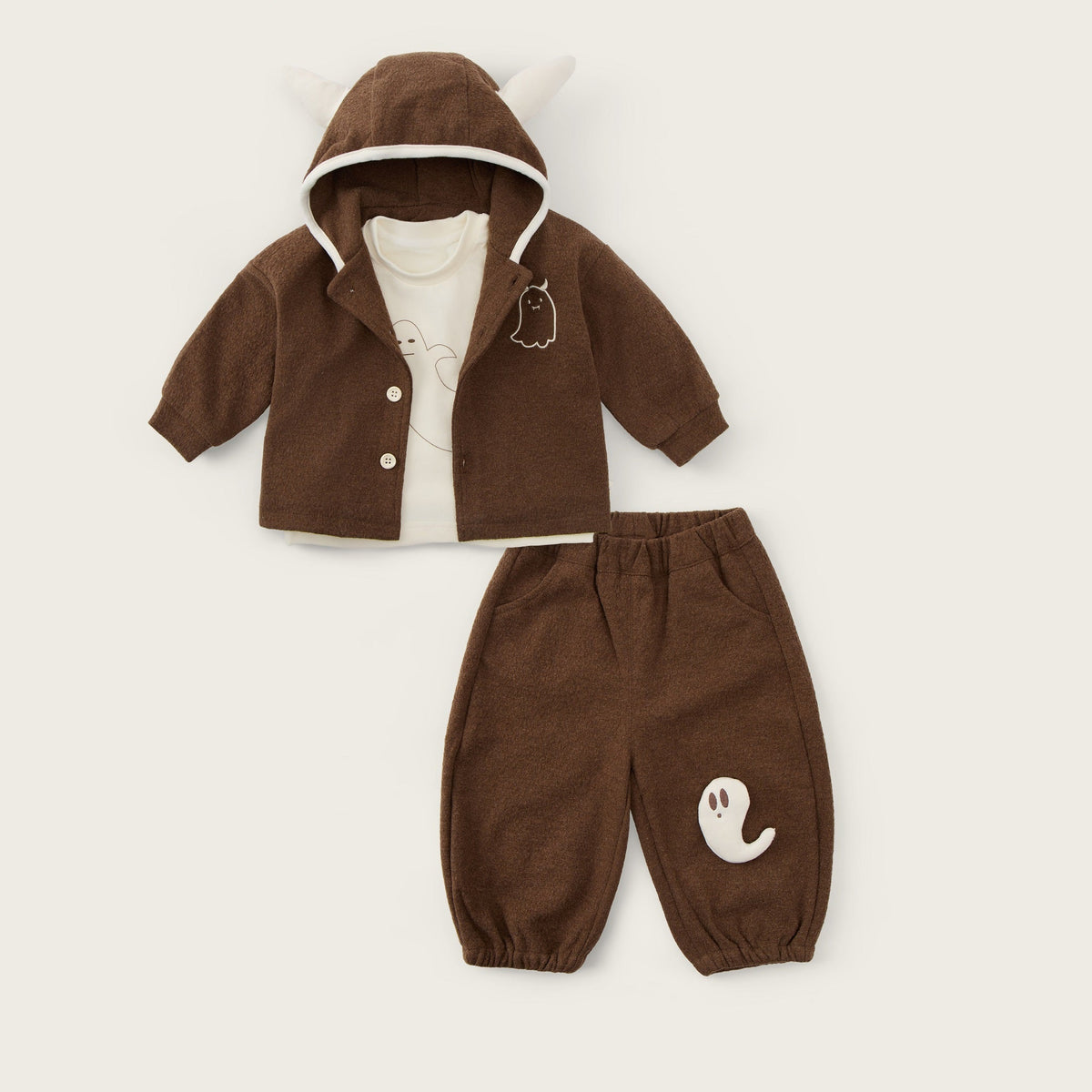 A baby clothing set displayed flat on a light beige background, featuring a brown hooded cardigan with white trim and a matching pair of brown pants with a white ghost graphic. The text 'jacinda bebe' is written at the top and 'lovely kids' at the bottom.