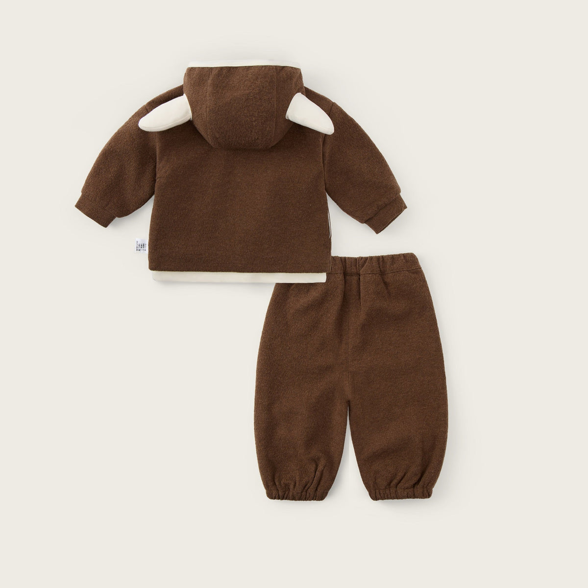 A two-piece baby outfit set in brown corduroy, featuring a hooded top with white ear details and matching pants, displayed on a light beige background with 'jacinda bebe' and 'lovely kids' text.