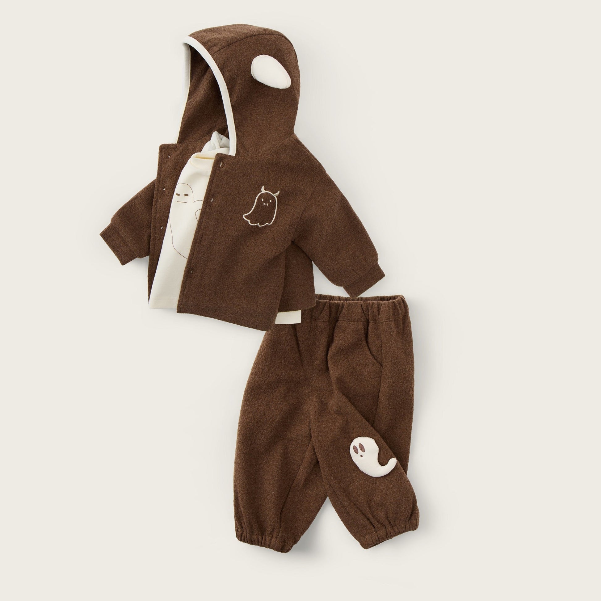 A two-piece baby outfit set in brown corduroy, featuring a hooded jacket with a white-trimmed hood and matching pants, displayed on a light beige background with decorative text.