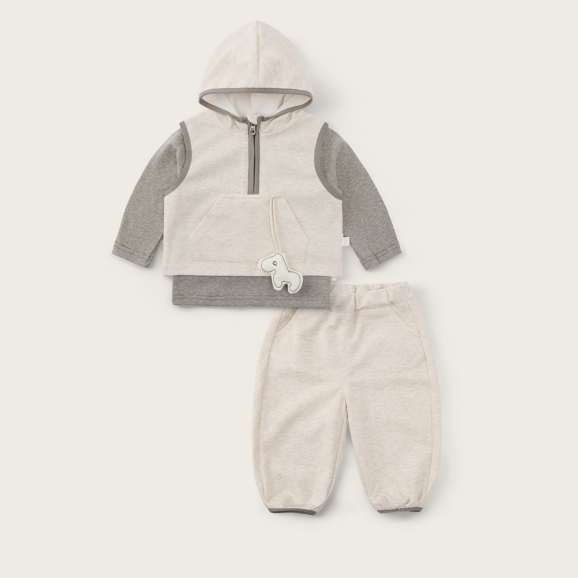 A baby clothing set featuring a cream-colored hooded vest with gray sleeves and a half-zip front, paired with matching cream pants. The set is displayed flat on a light beige background with 'jacinda bebe' written at the top and 'lovely kids' at the bottom.