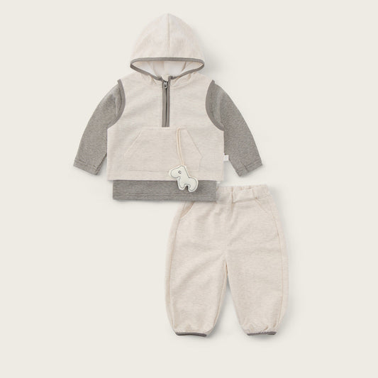 A baby clothing set featuring a cream-colored hooded vest with gray sleeves and a half-zip front, paired with matching cream pants. The set is displayed flat on a light beige background with 'jacinda bebe' written at the top and 'lovely kids' at the bottom.