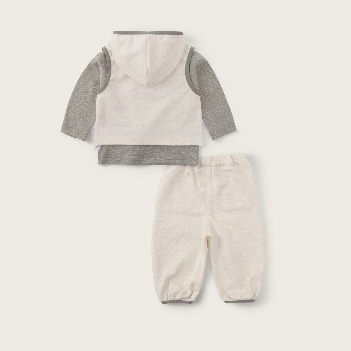 Baby two-piece outfit set featuring a hooded long-sleeve top and matching pants in a cream and heather gray colorway, displayed on a light beige background with 'jacinda bebe' and 'lovely kids' text.