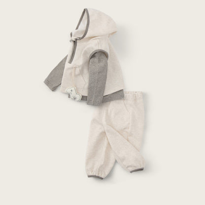 A baby clothing set laid flat on a warm off-white background, featuring a cream hooded vest with gray sleeves and matching cream pants. The text 'jacinda bebe' appears at the top and 'lovely kids' at the bottom.