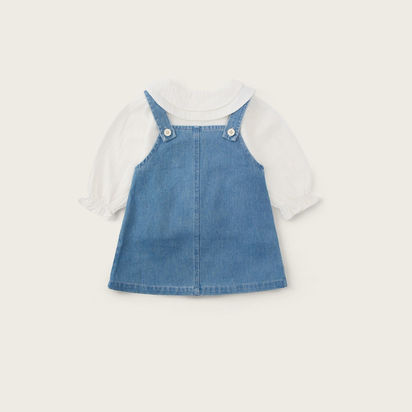 A baby girl's denim overall dress layered over a white short-sleeve bubble shirt, displayed flat against a light beige background with 'jacinda bebe' at the top and 'lovely kids' at the bottom.