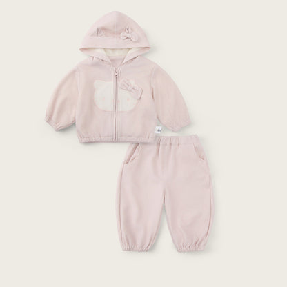 A baby girl's two-piece clothing set in a soft light pink, featuring a zip-up hooded jacket with a bear face applique and matching jogger pants. The set is displayed flat on a warm off-white background with 'jacinda bebe' written at the top and 'lovely kids' at the bottom.