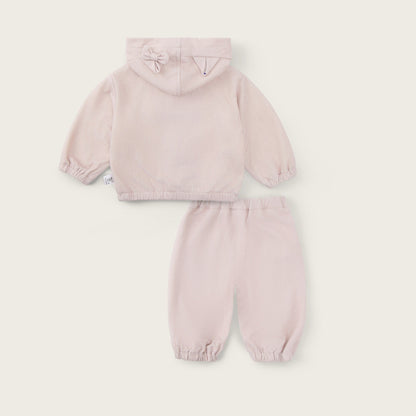 A two-piece baby outfit set in a very pale blush pink, featuring a hooded sweatshirt and matching jogger pants, displayed on a light cream background with 'jacinda bebe' and 'lovely kids' text.