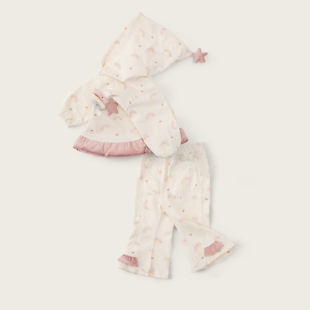 A baby sleepwear set laid flat on a warm off-white background, featuring a hooded top and matching pants in a soft cream fabric with tiny pink star prints and pink ruffle trim. The text 'jacinda bebe' appears at the top and 'lovely kids' at the bottom.