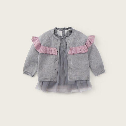 A baby girl's gray knit cardigan with pink ruffle accents on the shoulders, layered over a matching gray tulle dress, shown against a light beige background with 'jacinda bebe' and 'lovely kids' text.