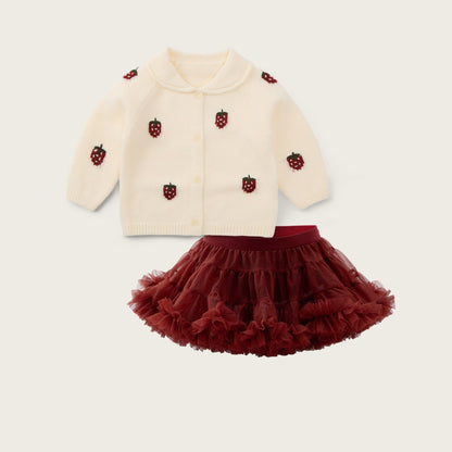 A baby girl's two-piece outfit set featuring an off-white knit cardigan with embroidered red strawberries and a matching dark red ruffled tutu skirt, displayed on a light beige background with 'jacinda bebe' and 'lovely kids' text.