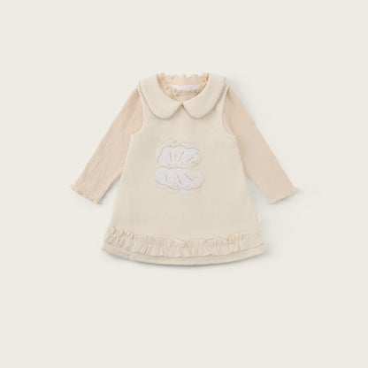 A cream-colored baby dress with long beige sleeves, a Peter Pan collar, and a white embroidered monogram on the front, displayed on a light beige background with 'jacinda bebe' at the top and 'lovely kids' at the bottom.