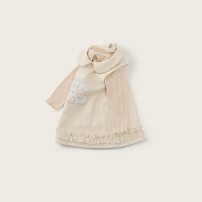 A cream-colored baby cape with a wide collar and a white embroidered flower on the chest, displayed on a light beige background with 'jacinda bebe' at the top and 'lovely kids' at the bottom.