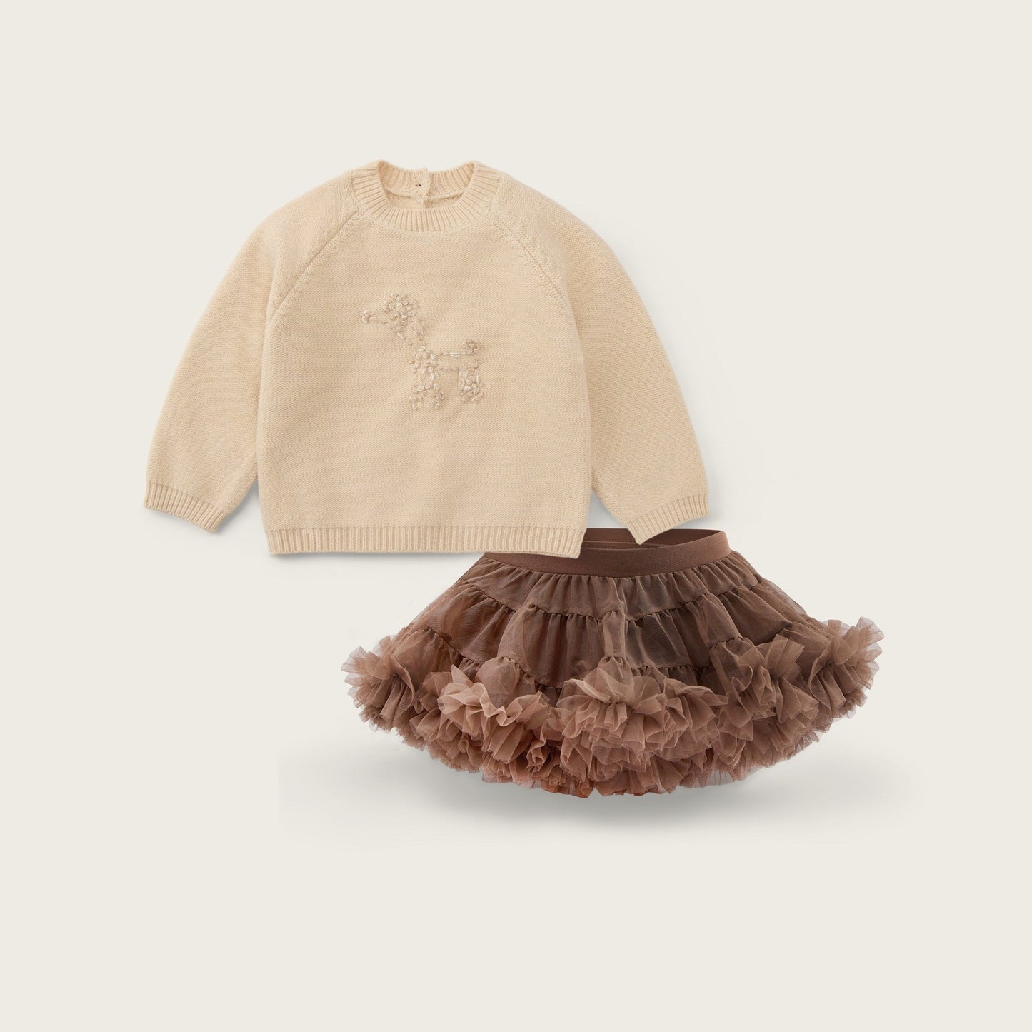 A baby girl's two-piece outfit set featuring a beige long-sleeve knit sweater with a subtle embroidered design and a brown ruffled tulle tutu skirt, displayed on a light beige background with 'jacinda bebe' and 'lovely kids' text.