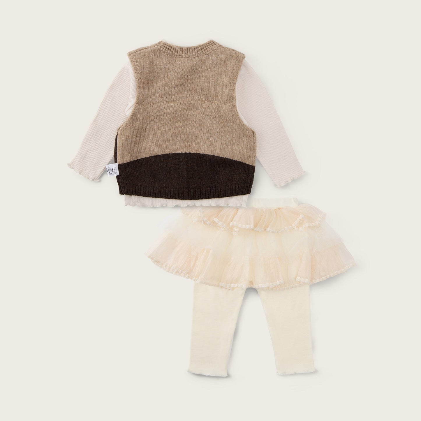A baby girl's two-piece knit outfit set by Jacinda Bebe, featuring a color-blocked vest with beige, brown, and cream panels over a cream long-sleeve shirt, paired with a cream ruffled tutu skirt and cream leggings. The brand names 'jacinda bebe' and 'lovely kids' are printed on the cream background.