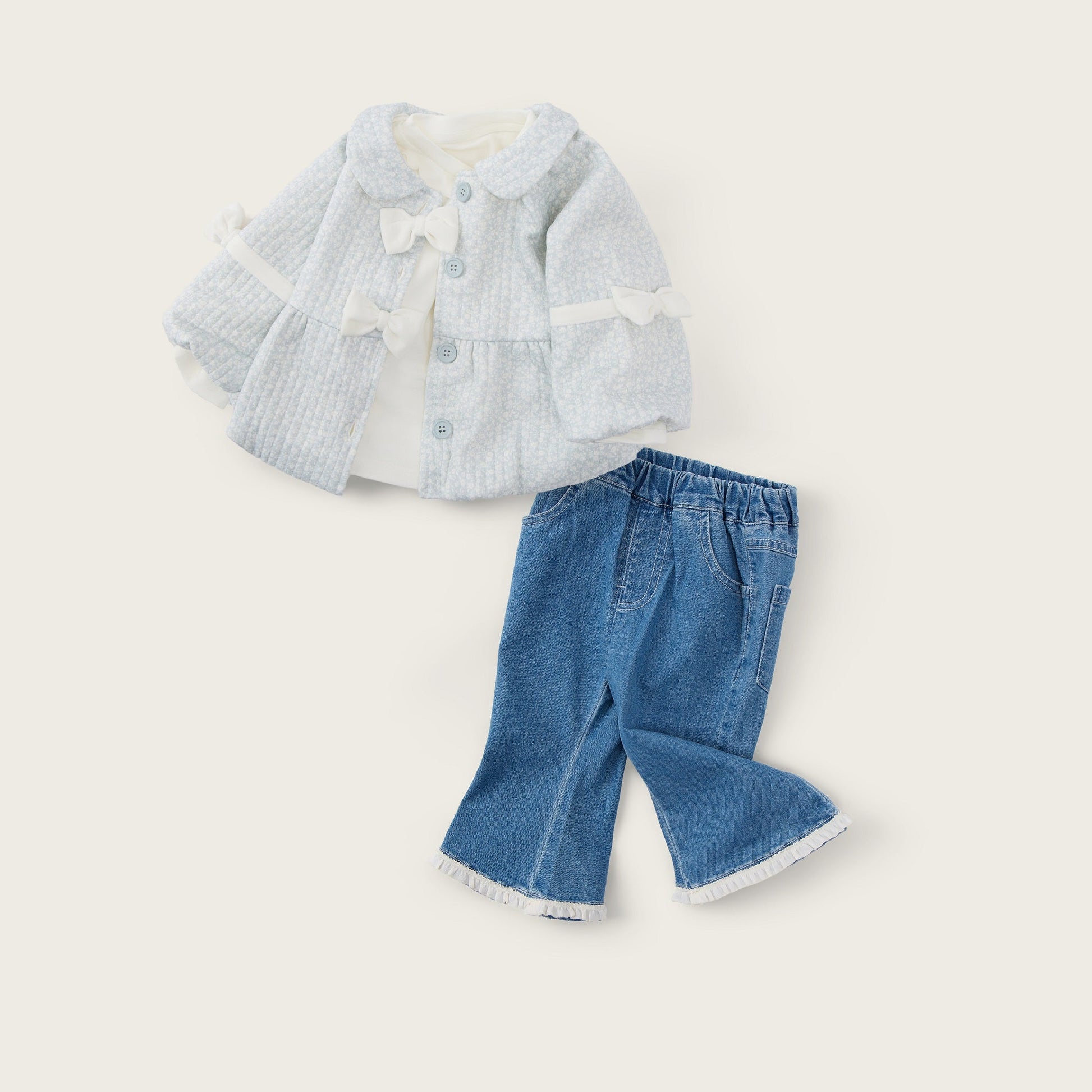 A two-piece doll or toddler outfit set featuring a light blue and white textured jacket with white lace trim and a bow, paired with blue denim pants with white lace trim, on a cream background with 'jacinda bebe' and 'lovely kids' text.