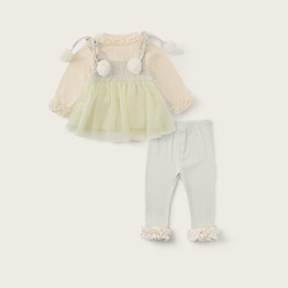 A baby girl's two-piece outfit set featuring a cream and pale yellow tulle dress with long sleeves and pom-pom details, paired with light gray leggings with ruffle cuffs. The image is presented on a warm cream background with 'jacinda bebe' at the top and 'lovely kids' at the bottom.