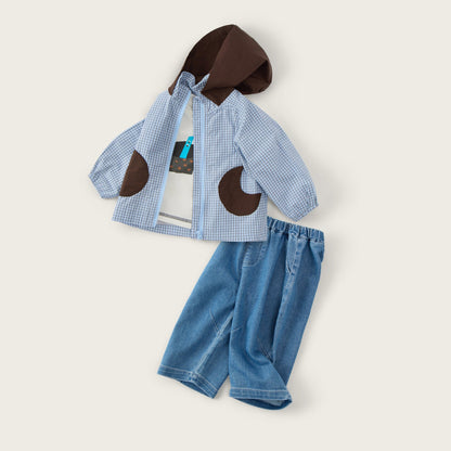 A children's outfit set laid flat on a light beige background, featuring a light blue and white gingham jacket with dark brown hood and patch details, paired with matching blue denim shorts. The text 'jacinda bebe' appears at the top and 'lovely kids' at the bottom.