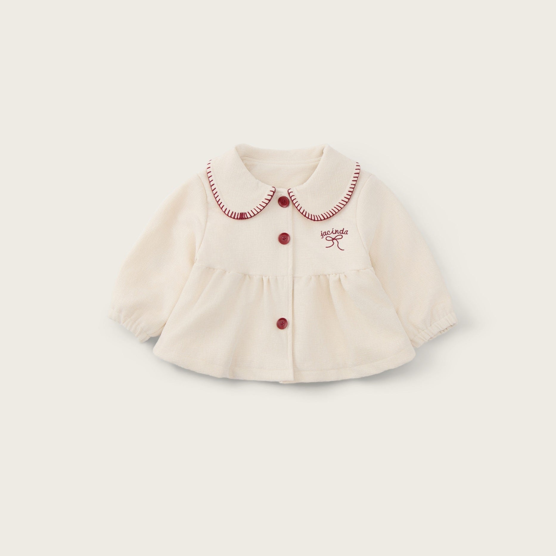 An off-white baby cardigan with a Peter Pan collar, red buttons, and red embroidered details, displayed on a light beige background with 'jacinda bebe' and 'lovely kids' text.
