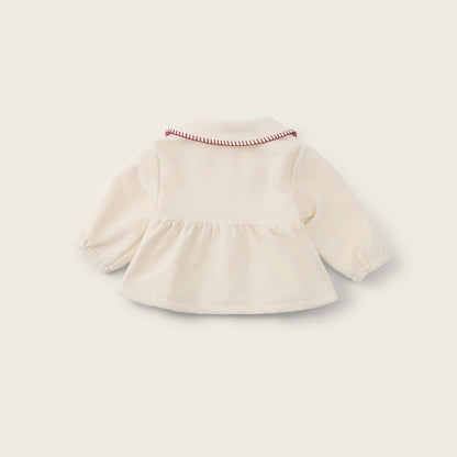 A cream-colored long-sleeve baby top with a ruffled hem and a delicate red-and-white striped collar trim, shown from the back on a light beige background with 'jacinda bebe' and 'lovely kids' text.
